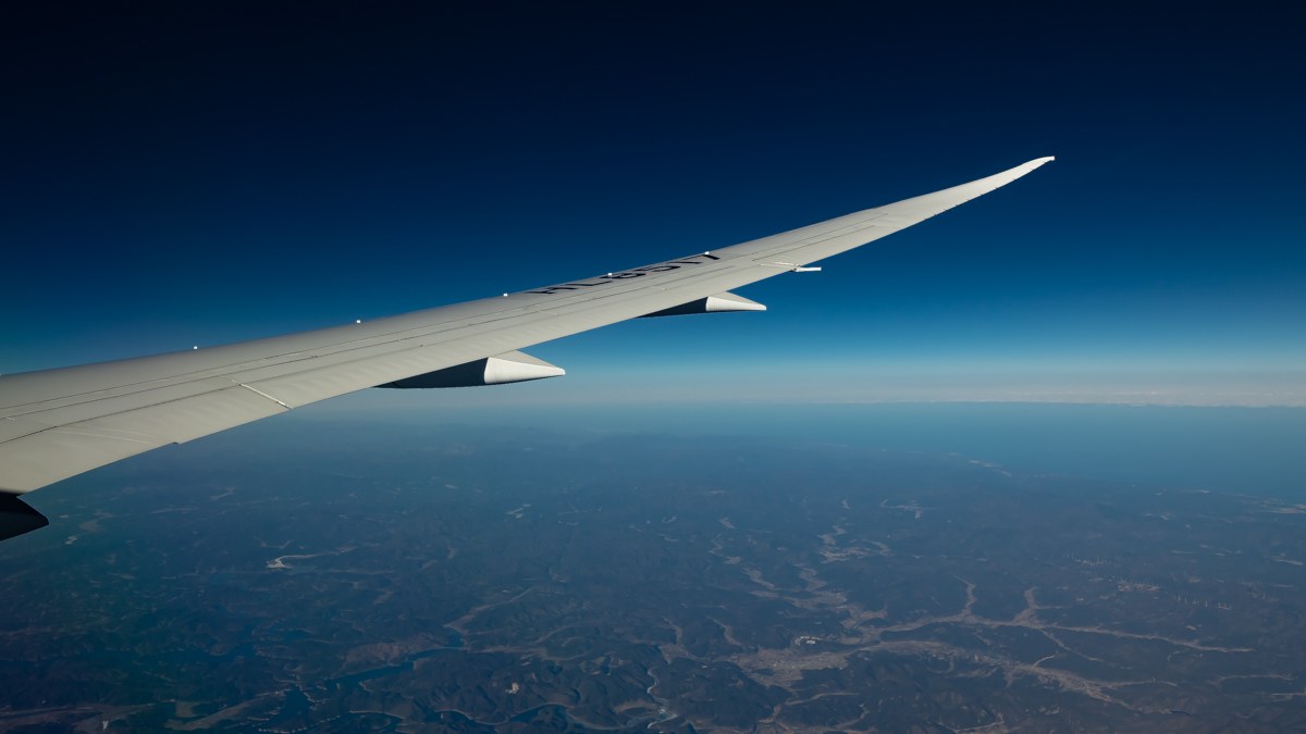 The wing of an aircraft above the Japanese coastline, seen from a window seat