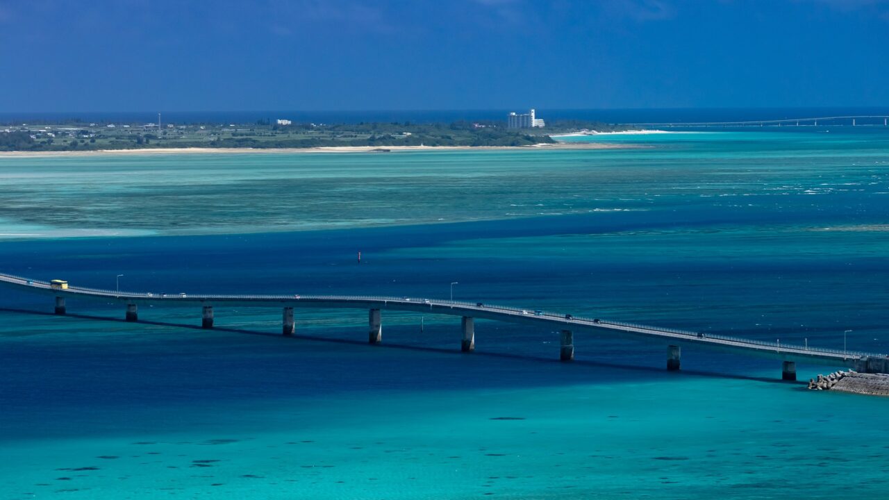 A long low road bridge running across shallow turquoise sea between two islands