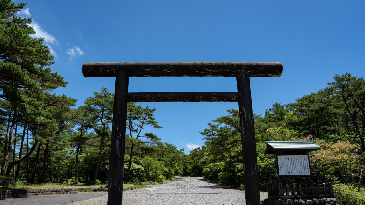 A large plain wooden torii standing over a gravel approach