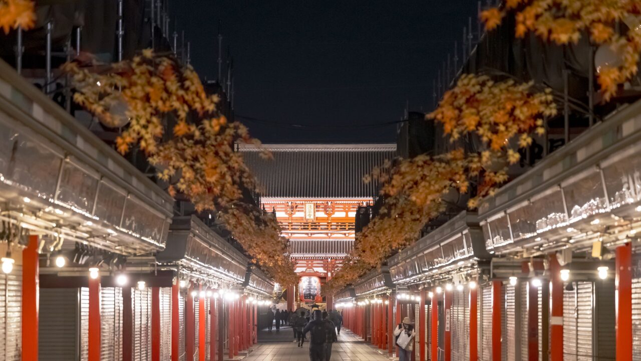 A covered shopping street lined with red-painted stalls, empty at night