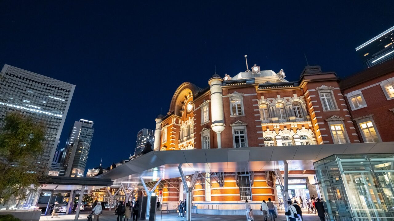 A long red brick station building floodlit at night