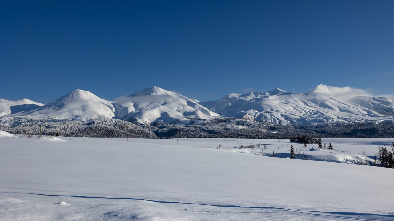 A snow-covered plain in front of a long line of white mountains