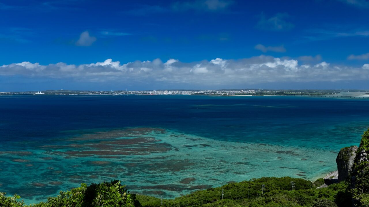 Shallow turquoise water over a coral reef seen from a green headland