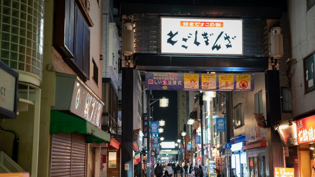 A covered shopping arcade with projecting shop signs receding into the distance