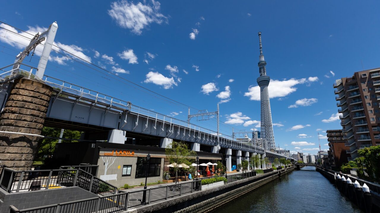An elevated railway crossing a canal between low-rise buildings